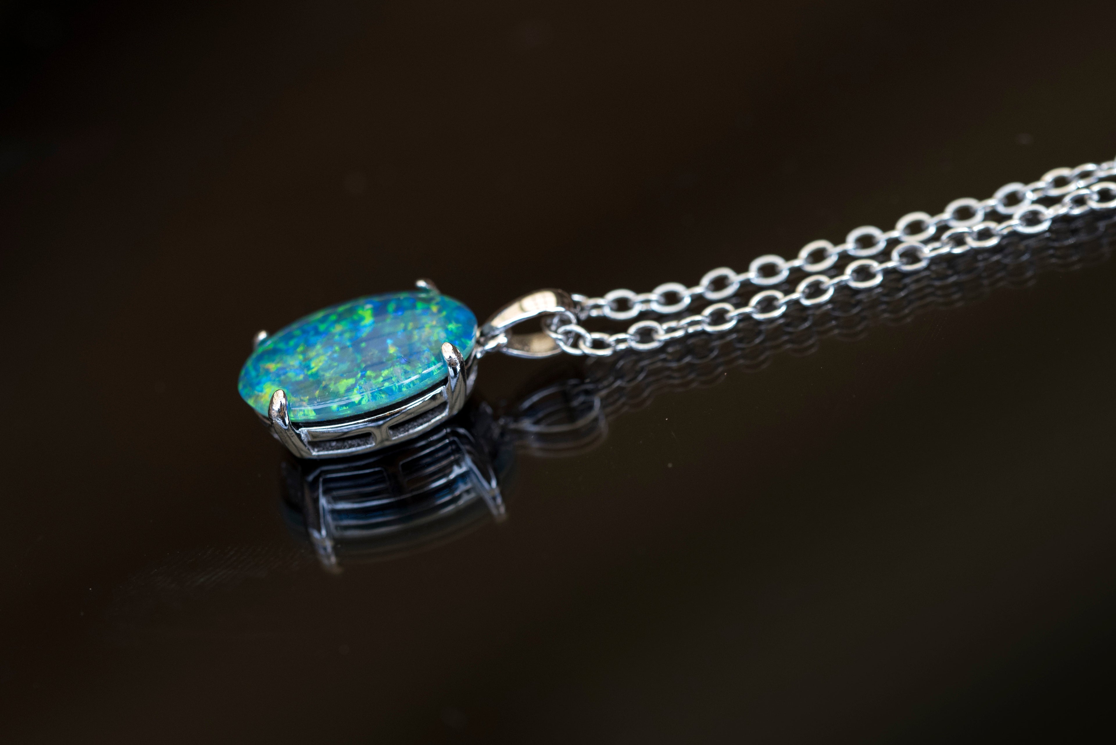 Opal pendant on a chain against a dark background
