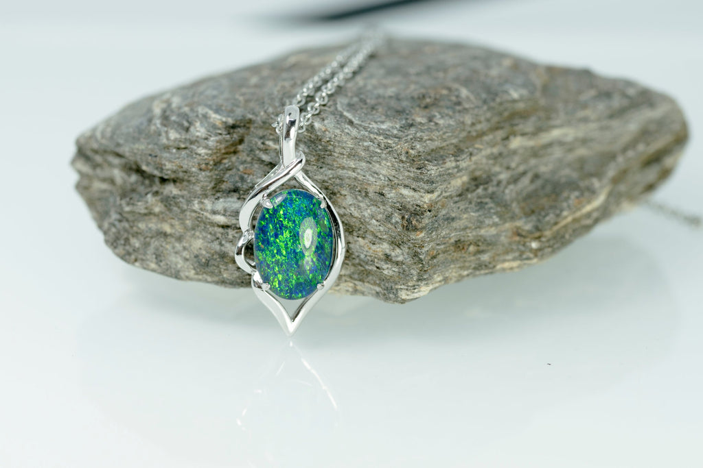 Opal pendant necklace on a rock with a white background