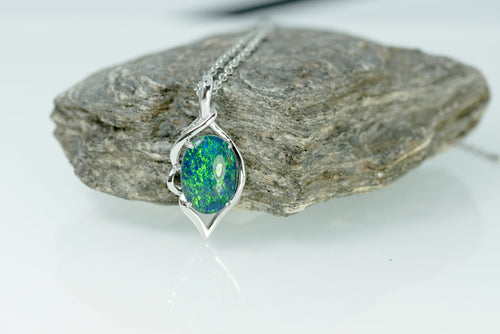 Opal pendant necklace on a rock with a white background