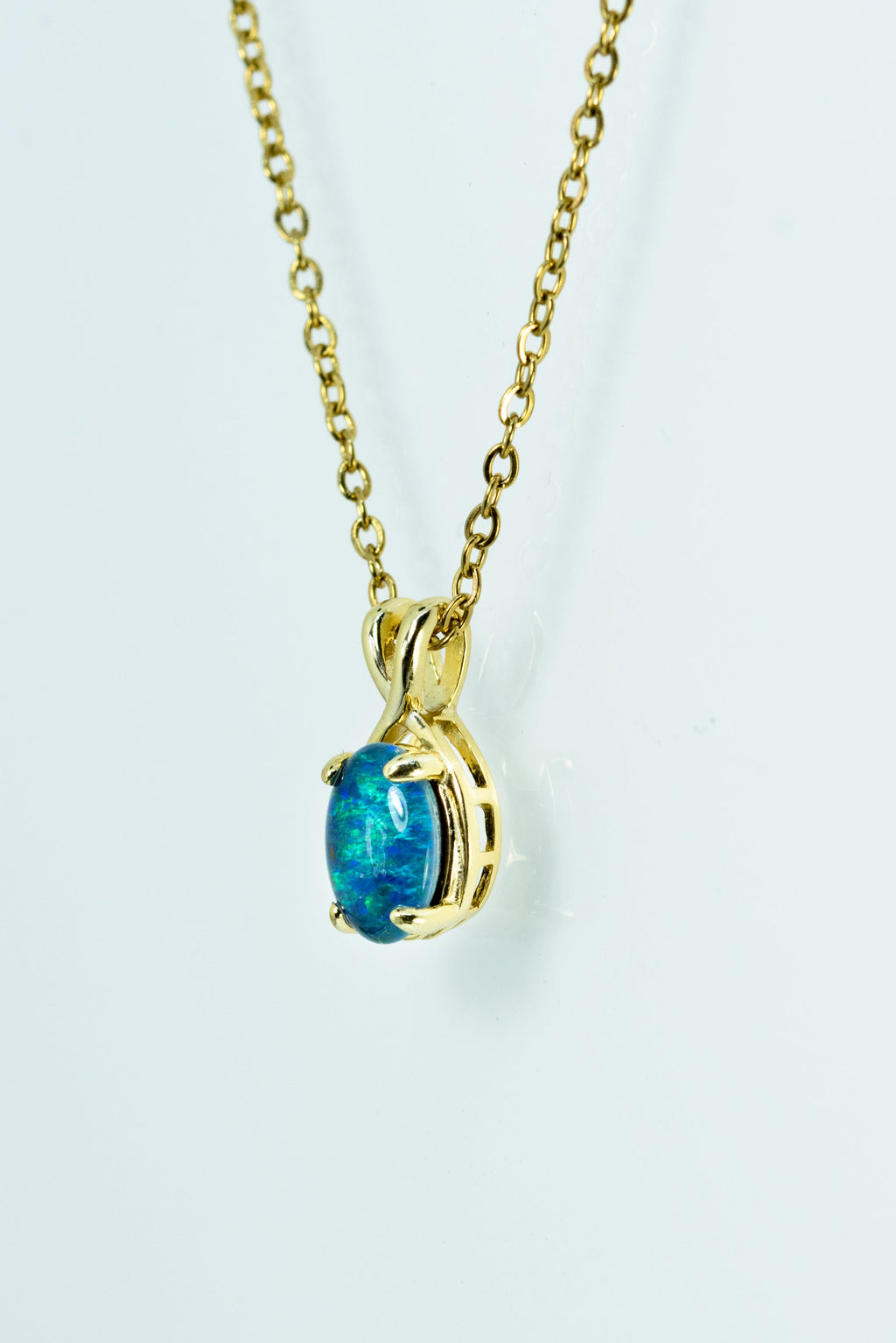 Gold necklace with a blue gemstone pendant on a white background
